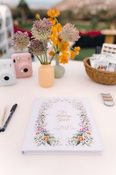 a white table topped with flowers next to a camera and other items on top of it