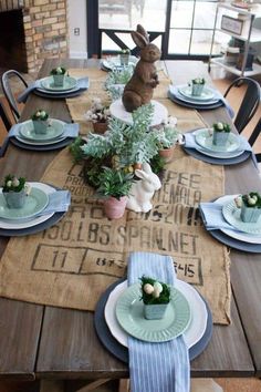 the table is set with blue and white plates, napkins and bunny figurines