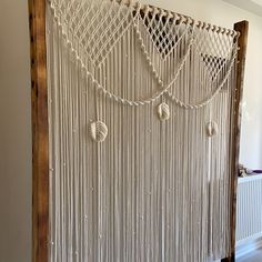 a white wall hanging with macrame balls and chains on it's sides