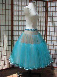 a mannequin wearing a blue tulle skirt in front of a white wall