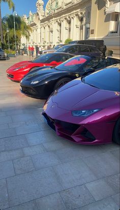 several different colored sports cars parked in front of a building