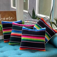 four colorful pillows sitting on top of a blue couch