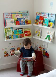 a toddler sitting on a chair in front of a bookshelf