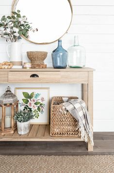 a wooden table topped with pictures and vases next to a wall mounted round mirror