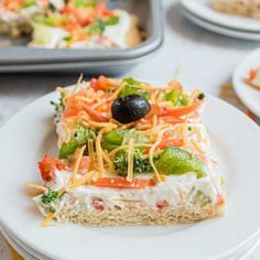 a piece of pizza with cheese and vegetables on it sitting on a plate next to other plates