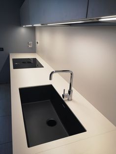 a white counter top with a sink and faucet in the corner next to it