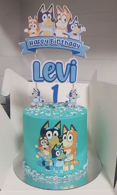 a blue birthday cake with cartoon characters on it's top and the number one candle