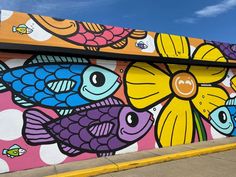 a colorful mural on the side of a building with fish and flowers painted on it