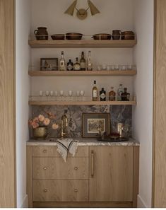 the shelves in this kitchen are filled with bottles and glasses