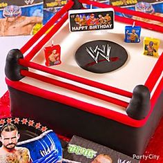 a birthday cake with the wwe logo on it and wrestling memorabilia in front of it