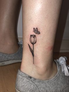 a woman's foot with a small flower tattoo on her left side ribcage