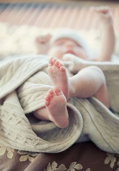 a baby wrapped in a blanket laying on top of a bed