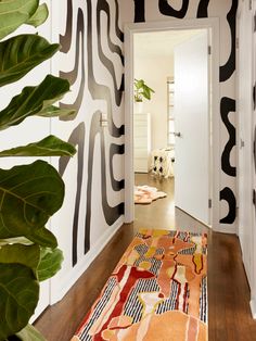 the hallway is decorated with black and white wallpaper, an orange rug, and a large green plant