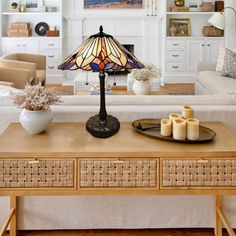 a living room filled with furniture and a lamp on top of a wooden coffee table