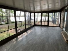 an empty room with large windows and wood flooring on the outside wall is shown