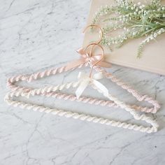 three pink and white hair ties on top of a marble table next to a plant