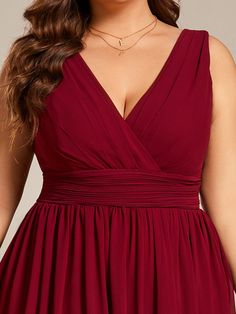 a woman in a red dress with her hands on her hips and wearing a necklace