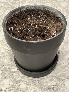 a potted plant with dirt in it sitting on a marble counter top next to a tile floor