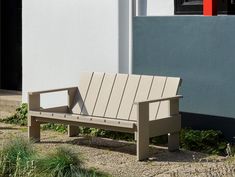 a bench sitting in front of a building next to grass and bushes on the ground