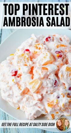 a white plate topped with fruit salad on top of a blue wooden table and text overlay reads top pinterest ambrosia salad get the full recipe salty side dish