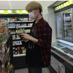 a woman wearing a face mask while looking at food in a grocery store display case