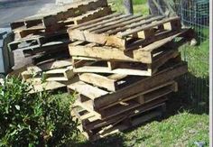 several wooden pallets stacked on top of each other in the grass next to a fence