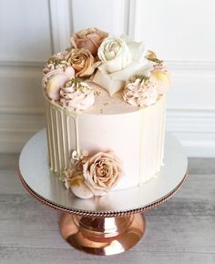 there is a white cake with flowers on the top and bottom, sitting on a stand