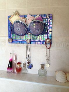 there are many items on the shelf in this bathroom that is decorated with mosaic tiles