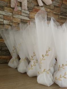 some white bags with gold leaf designs on them sitting on a wooden table next to a brick wall