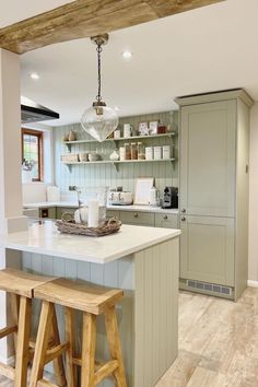 a kitchen with two stools in front of the island and shelves on the wall