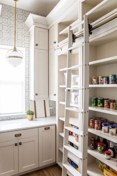 a kitchen with white cabinets and shelves filled with food