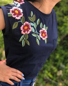 a woman with her hand on her hip wearing a blue shirt and flowered top