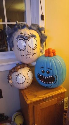 three pumpkins with faces painted on them sitting next to each other in front of a window