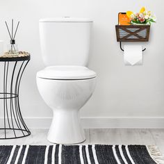 a white toilet sitting in a bathroom next to a black and white towel rack with flowers on it