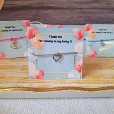 two bracelets with hearts attached to them sitting on top of a wooden table next to some cards