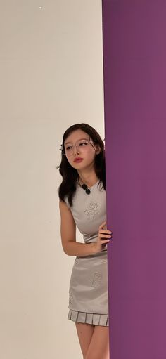 a woman is standing behind a purple wall