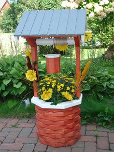 a flower pot with yellow flowers in it sitting on top of a red brick structure