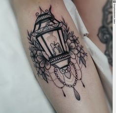 a woman's arm with a lantern and flowers tattoo on the left side of her body