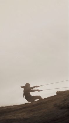 two people are flying kites on the top of a hill