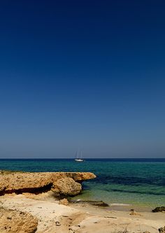 there is a boat that is out in the water on the beach near some rocks