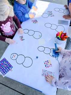 three children are sitting at a table and playing with their matching numbers on the paper