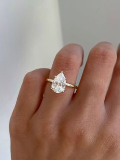 a woman's hand with a diamond ring on top of her finger, wearing a yellow gold band