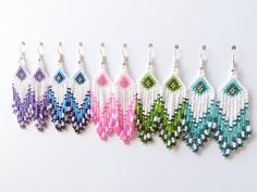 six pairs of beaded earrings hanging from hooks on a white surface, each with different colored seed beads