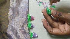 someone is working on some beading with green beads and pink flowers in the middle