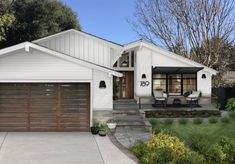 a white house with brown garage doors and windows