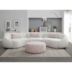 a living room with a large white sectional couch and round footstool on the rug