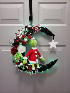 the grinch wreath is hanging on the front door with lights and decorations around it