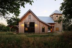 a large wooden house sitting on top of a lush green field next to tall grass