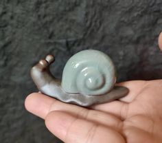 a small snail figurine sitting on top of someone's hand