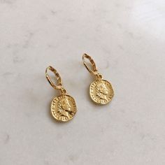 Dainty gold dangle coin earrings. These gold huggie earrings feature a tiny Italian lira coin charm. Delicate and yet eye catching. The ultimate accessory for every outfit, day to night. made of 14k gold plating over brass. Measurements: Diameter- 10mm Coin charm- 12xmm Shipping: Please allow 1-3 business days for your order to be processed and shipped. All orders are shipped in our customize box, gift ready. *Let me know if you have any questions and I will promptly respond Everyday Gold Plated Coin Jewelry, Yellow Gold Dangle Coin Pendant Jewelry, Yellow Gold Dangle Jewelry With Coin Pendant, Yellow Gold Coin Pendant Dangle Jewelry, Coin Shaped Earrings As A Gift, Nickel Free Gold Plated Circle Earrings, Nickel-free Gold Plated Circular Earrings, Elegant Yellow Gold Earrings With Coin Pendant, Dainty Gold Plated Coin Jewelry